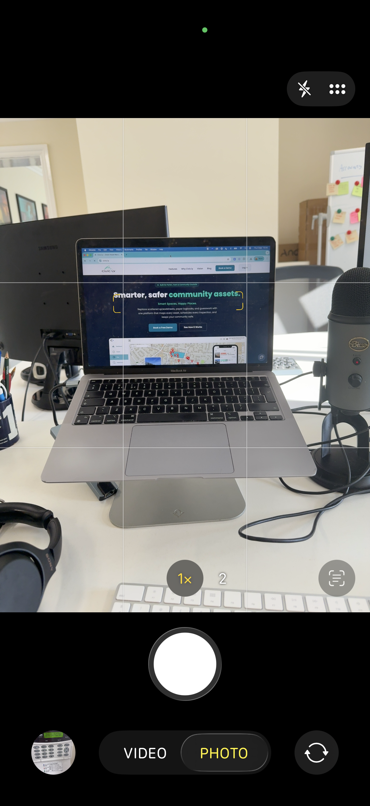 The iPhone camera app open and ready to take a photo of a laptop on a desk